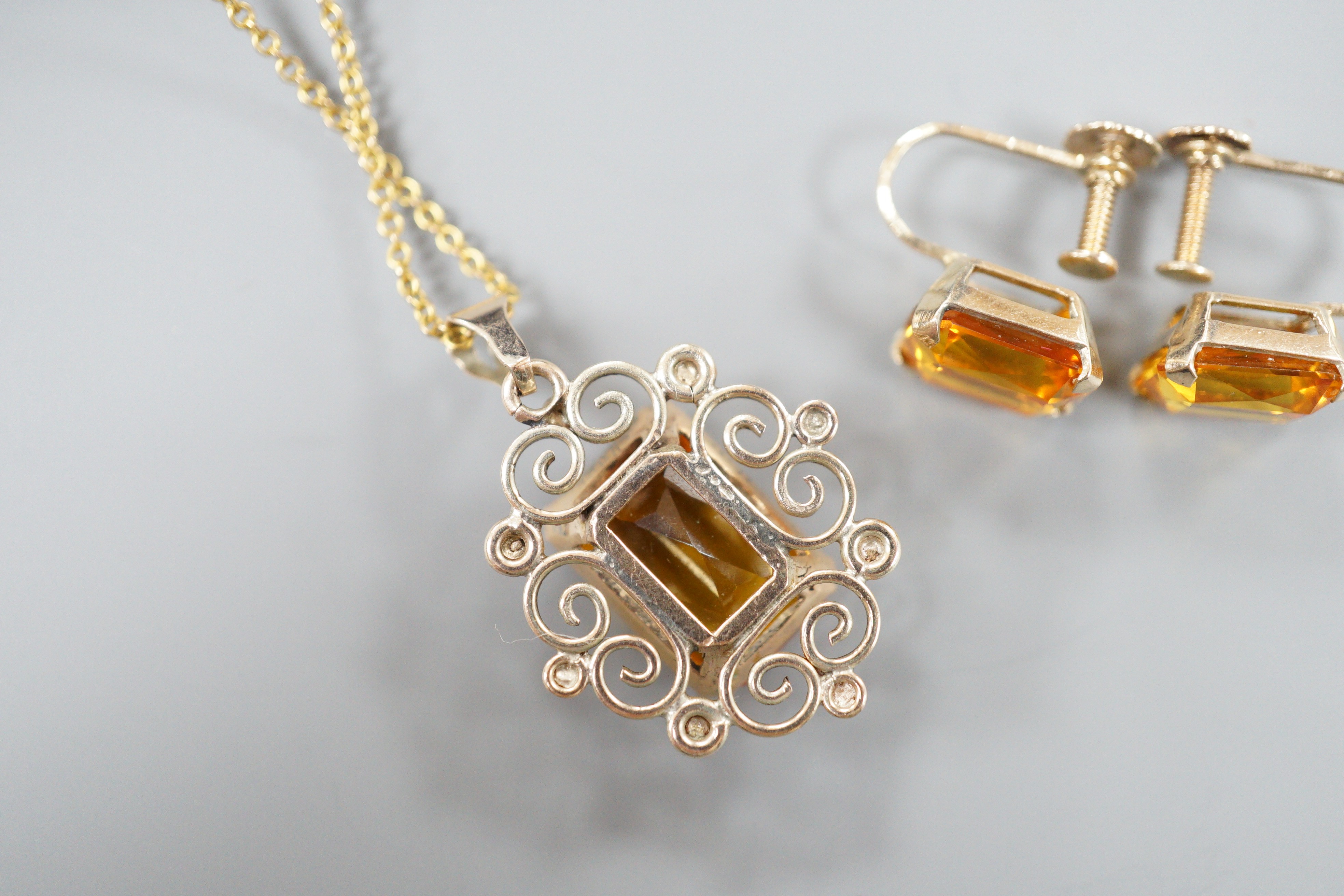 A yellow metal and citrine set pendant, 29mm, on a gold plated chain and a pair of 9ct and citrine set ear clips, gross 8.2 grams.